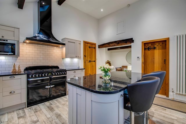 A stunning kitchen with fitted units and central island has an adjoining sitting space.