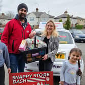 Kim Leadbeater, MP for Batley and Spen, shows off her basket of goodies collected from her 60-second Snappy Store Dash at Notay's Convenience Store, with all the products being donated to Batley Food Bank. Also pictured are store owner Serge and his two daughters.