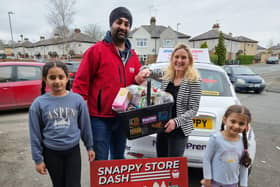 Kim Leadbeater, MP for Batley and Spen, shows off her basket of goodies collected from her 60-second Snappy Store Dash at Notay's Convenience Store, with all the products being donated to Batley Food Bank. Also pictured are store owner Serge and his two daughters.