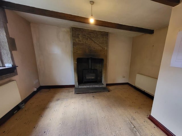 In the sitting room, the full height fireplace is a dominant feature, with its large hearth and wood burning stove.