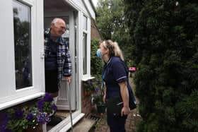 Hannah Poulter, community nurse, greets a service user at his door.