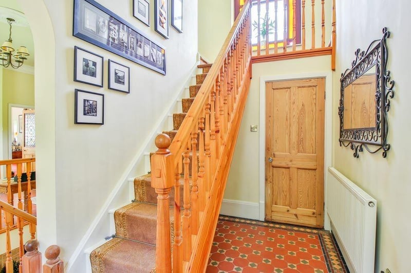 The bright hallway with a feature stained glass arched window at the top of the stairs.