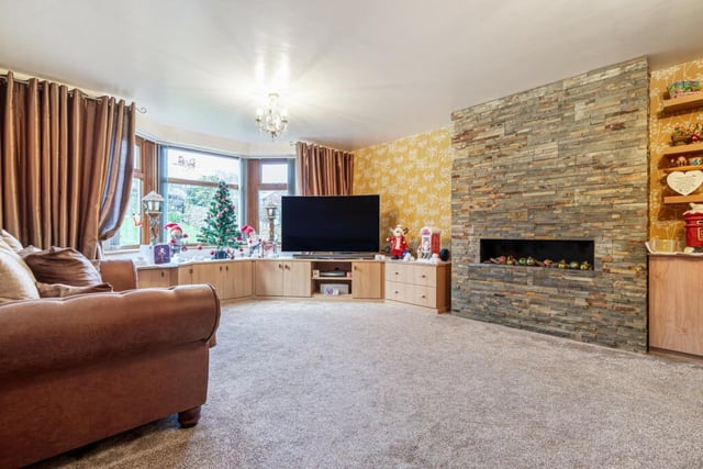 This reception room has a stone tiled feature wall with a modern open log gas fire.