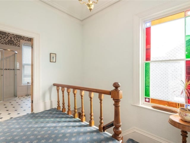 A large feature window with coloured glass lights up the stairway and landing area.