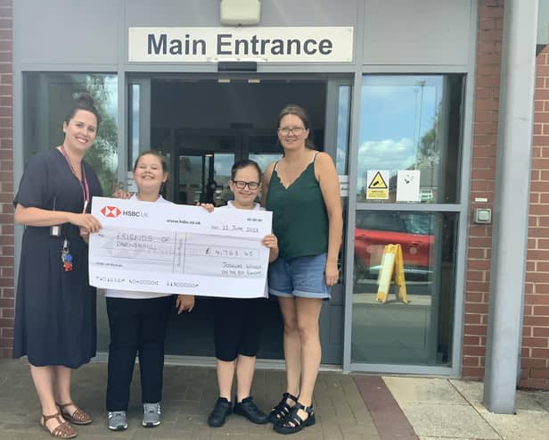 A cheque is presented to Charlotte Gray-Sharpe, fundraising manager at Ravenshall School, after the Joshua’s Wheels on the Bus Fun Day was held to raise money to help replace the school's stolen mini-buses. Joshua is also pictured, second to right.