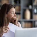 Head shot stressed young woman holding paper document, bank debt notification, thinking of financial troubles, looking away. Lost in negative thoughts depressed woman worrying about bad news notice.