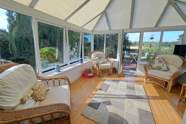 A spacious conservatory leads out to a raised seating area overlooking the river.