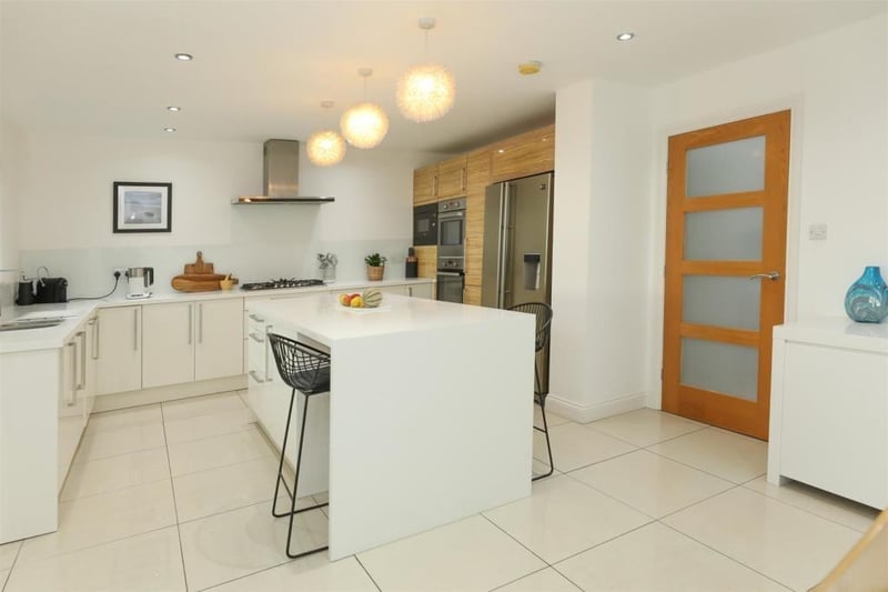 The modern, open plan kitchen has a central island with breakfast bar.