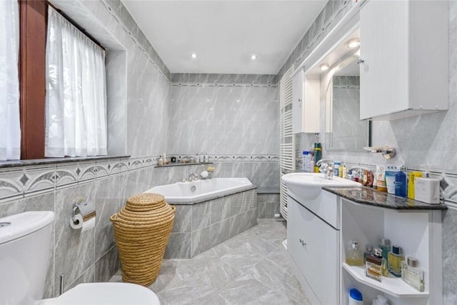 A fully tiled, luxurious bathroom with fitted units.