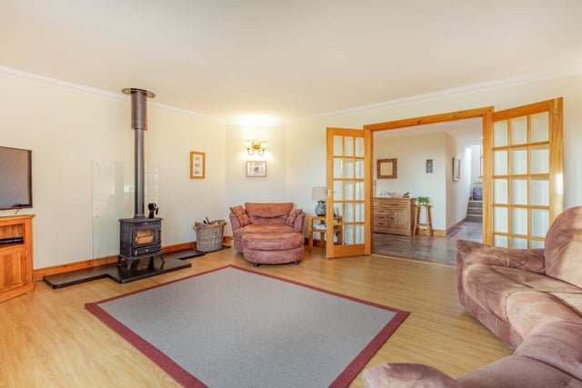 The spacious dual-aspect sitting room has a wood burning stove and glazed doors onto the patio area.