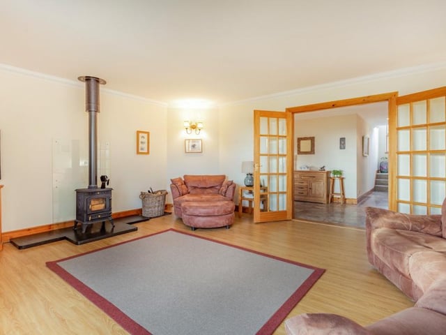 The spacious dual-aspect sitting room has a wood burning stove and glazed doors onto the patio area.