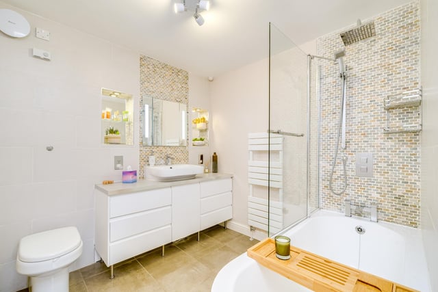 A stylish bathroom with wash basin in vanity unit, and bath with shower over.