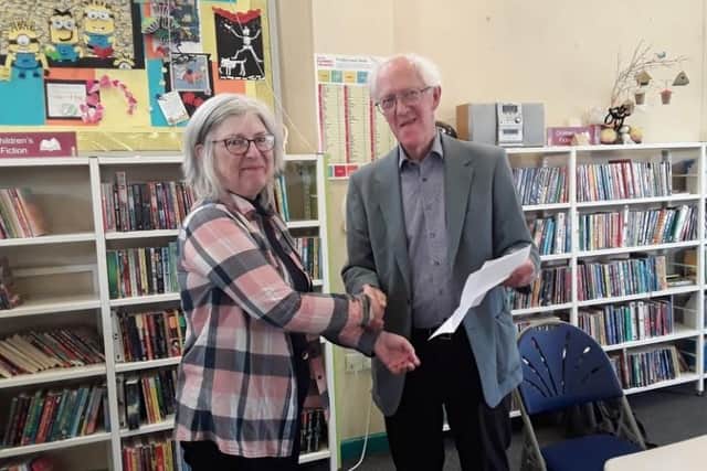 Hilary Wainwright, Treasurer of the Friends of Birstall Library, receiving a grant cheque from John Broadhead of the Batley and Birstall Community Fund, to help towards the fundraising efforts of the Mobii system.