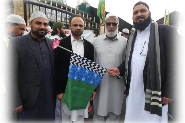 Some men holding a green and blue Sufi-Muslim flag
