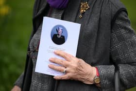 A mourner carries an order of service as they leave after attending the funeral of former Speaker of the House of Commons, Betty Boothroyd, at St George's Church in Thriplow, near Cambridge