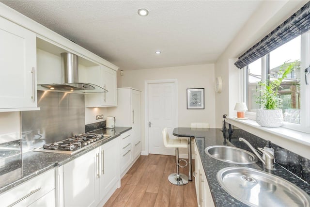 The kitchen features a modern range of wall and base units, complimentary worktops, a breakfast bar and inset sink with a drainer and mixer tap.