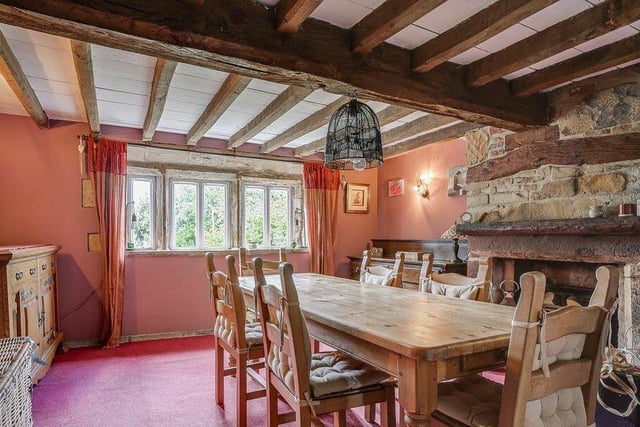A spacious, beamed dining room with an inglenook fireplace and mullion windows.