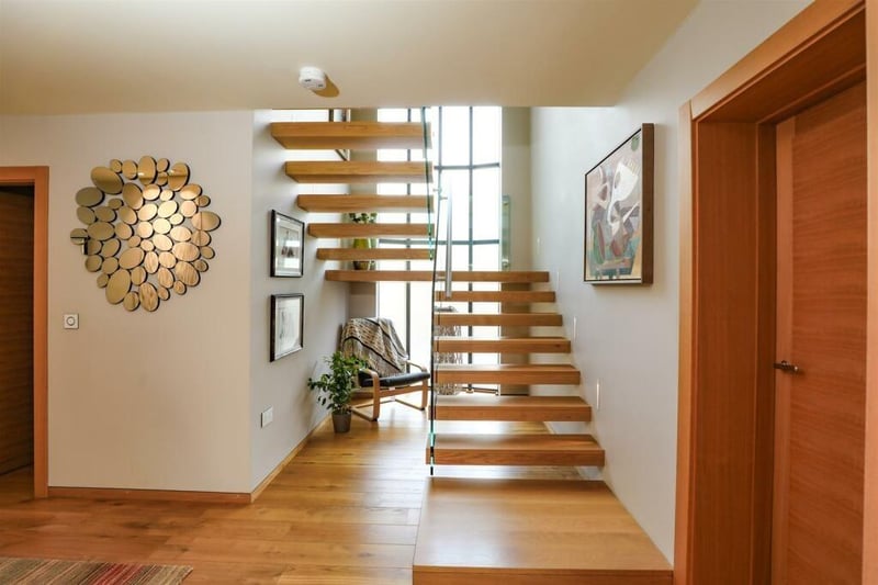A timber staircase with glass balustrade leads to the first floor from the hallway.