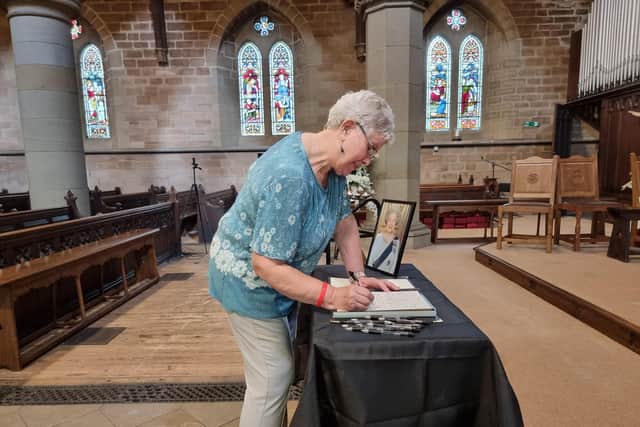 A member of the public signs in the book of condolence at Saint Mary's Church, Mirfield