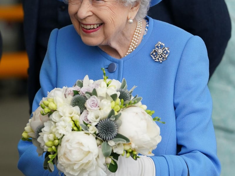 Queen Elizabeth II receives flowers as she meets employees.
