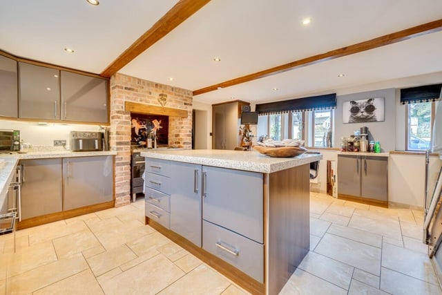 The spacious kitchen with central island has integrated appliances and space within the chimney breast for a range style cooker.