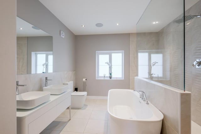 A contemporary bathroom with freestanding bath and twin wash basins.