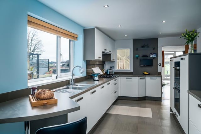 A modern kitchen with integrated appliances and breakfast bar.