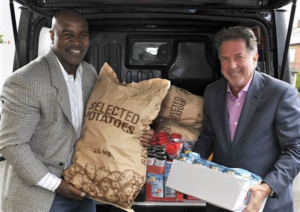 BOXING CLEVER Evander Holyfield with Global Village Champions Foundation chairman Yank Barry deliver food for local projects.