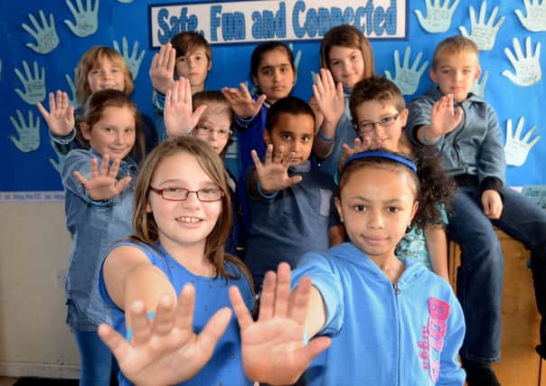 Pupils at Bywell School are dressed in blue for anti-bullying week , infront of  a wall display with hand-prints containing anti-bullying messages on and they have also sold anti-bullying wrist bands. (d621a347)
