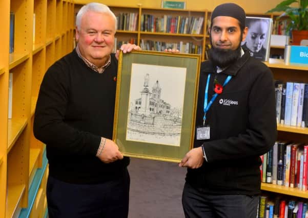 Tony Dunlop handing over art to Mohammed Salloo and the Batley library. (D522A445)