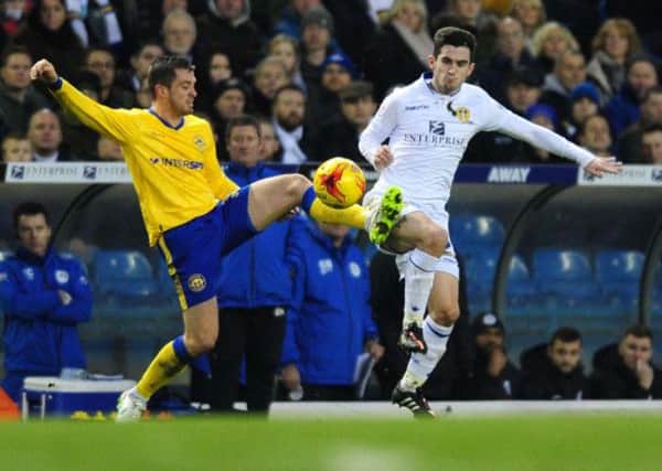 Leeds United's Lewis Cook battles for the ball with Wigan's Andy Taylor.