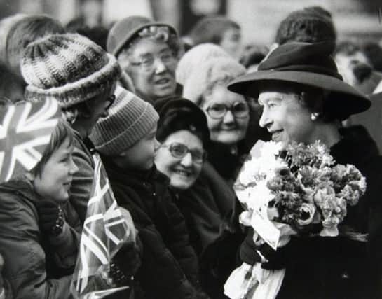 25th November 1982. The Queen chats with children in the crowd waiting to greet her in a Wakefield pedestrain precinct.