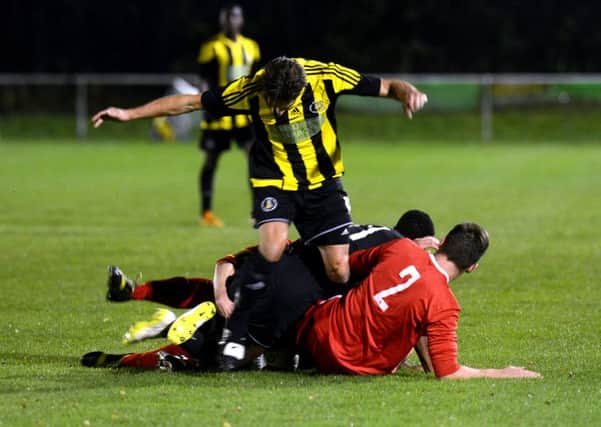 Nostell's Simon Poole falls under a challenge from the Liversedge goalkeeper and a defender last Friday.