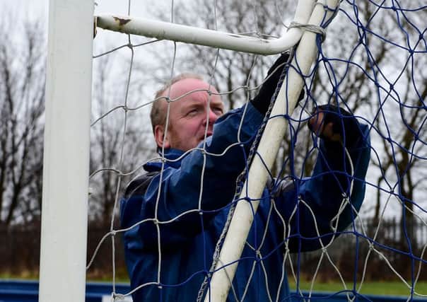 Liversedge groundsman Andrew Taylor takes down the nets after seeing another home game postponed.