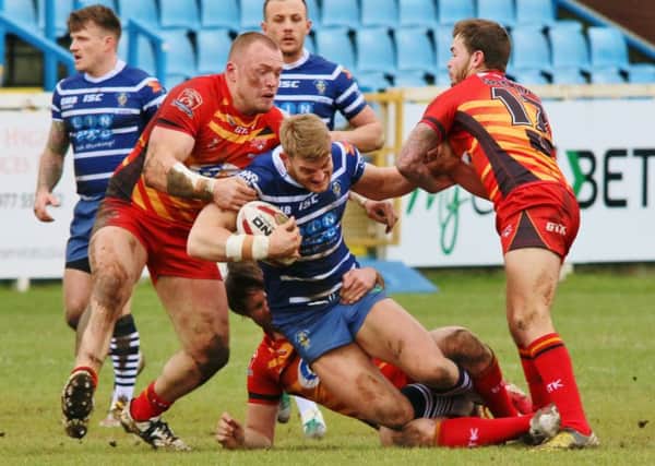Featherstone's Jack Ormondroyd is hauled to the ground by Dewsbury tacklers. Picture: Carol Austerberry.
