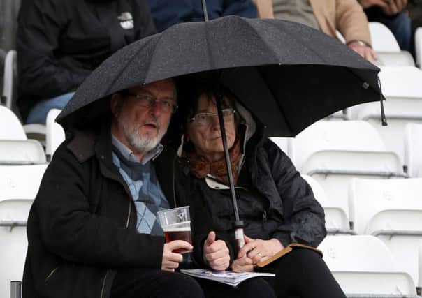 Spectators shelter under an umbrella during a break for rain at Headingley yesterday (Picture: Simon Cooper/PA Wire).