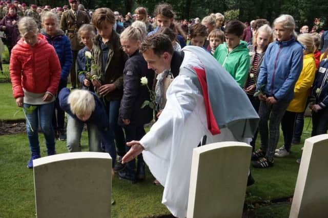 Local school children from Oosterbeek lay flowers on LCpl Loneys grave with the assistance of Reverend Dr Brutus Green, at the service for LCpl William Loney, of Dewsbury. Picture: Crown Copyright