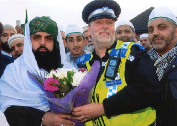 PCSO Chris Pooley presents flowers on behalf of everyone at Dewsbury Police Station to Mufti Shaiykh Allama Moalana Noor-Ul-Arifin.