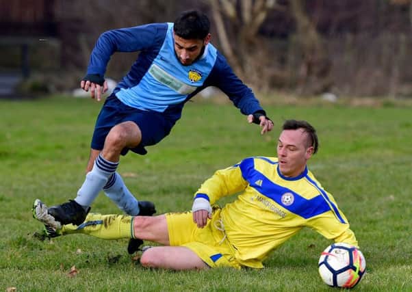 Ravenswharfe's uane Fascoine slides in to tackle Mount Pleasant's Muhammad Omar during the Heavy Woollen Sunday League Championship clash.