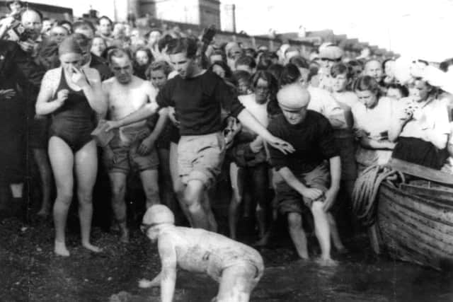 EPIC EFFORT: Eileen Fenton crawls to victory with a badly injured shoulder as the crowds are held back. If anyone had given her a helping hand she would have been disqualified. She had to completely clear the water before being hailed first woman home in this epic channel race in 1950.